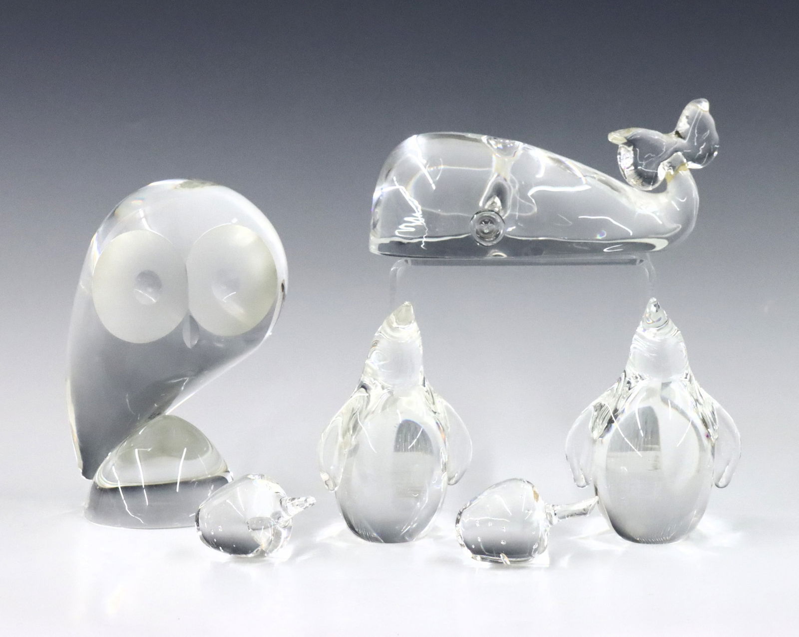 6 Steuben Crystal Figures: Six mid to late 20th century Steuben Crystal figures. Includes an owl designed by Donald Pollard, a whale by Lloyd Atkins, two penguins and two apples. Animals with etched "Steuben" signatures, apples
