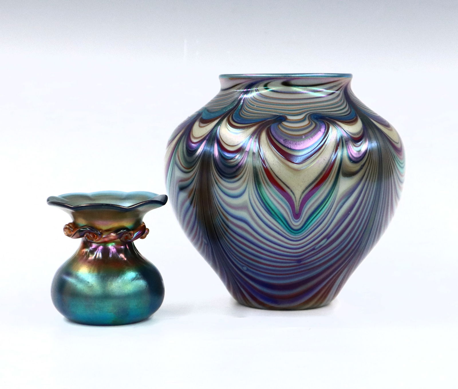 2 Vintage Art Glass Vases: Two pieces of vintage 1970's Art Glass. Includes an Orient & Flume vase with bulbous form and Iridescent Pulled Feather design, and a Robert Hansen Carnival Glass spittoon posy vase with corseted form