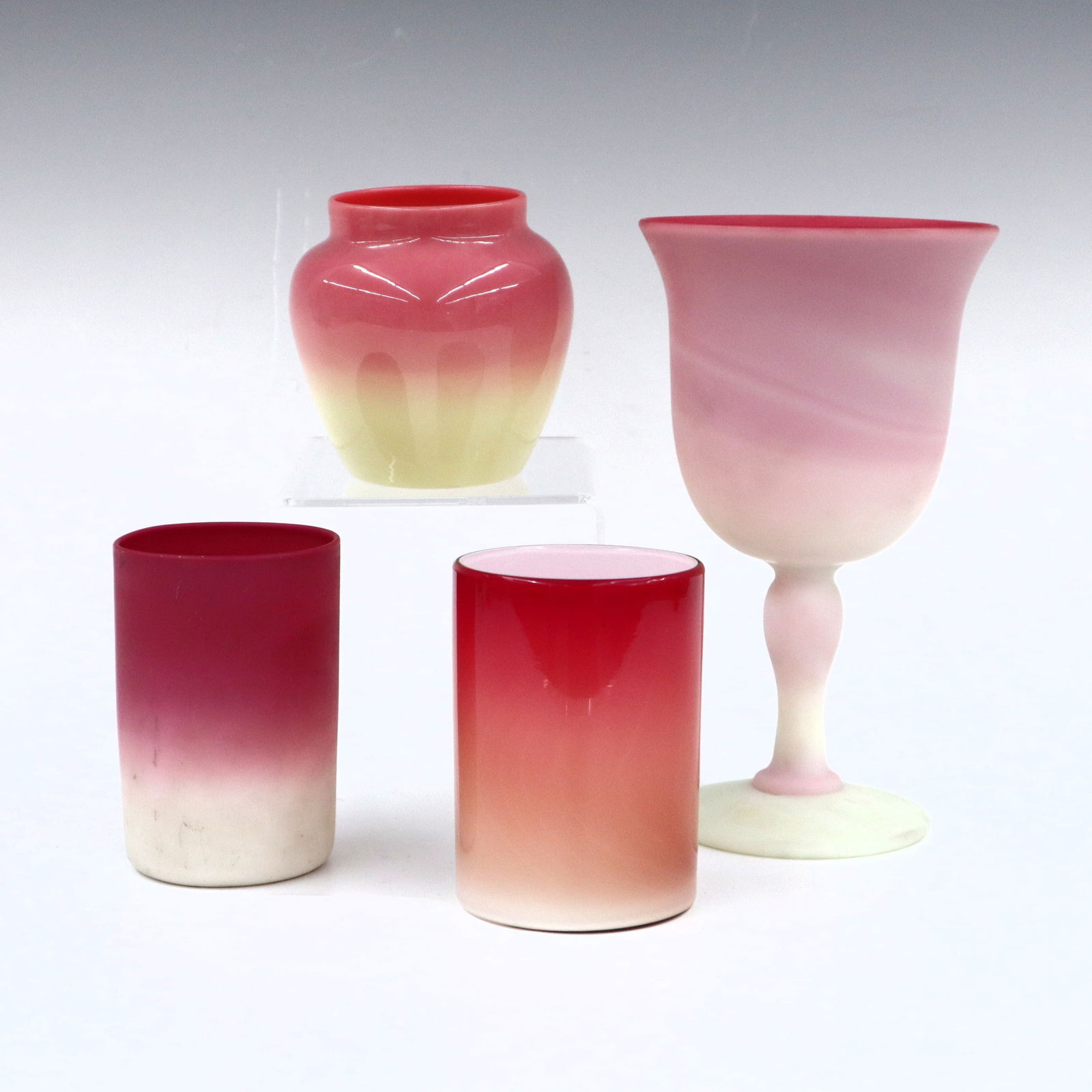 4 pc Burmese & Peach Blow Art Glass: Four pieces of turn of the century Burmese and Peach Blow Art Glass. Includes a satin Burmese water goblet, shiny Burmese juice glass and jar, and a shiny Peach Blow juice glass. Minor surface wear, s