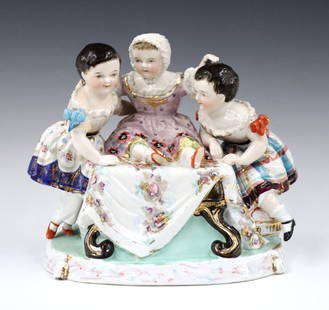 Meissen Style Figural Group: An early 20th century Meissen style porcelain figural grouping. Depicts three little girls seated on and around a table with polychrome hand-painted decoration and Gilded detail. Unmarked, painted "37