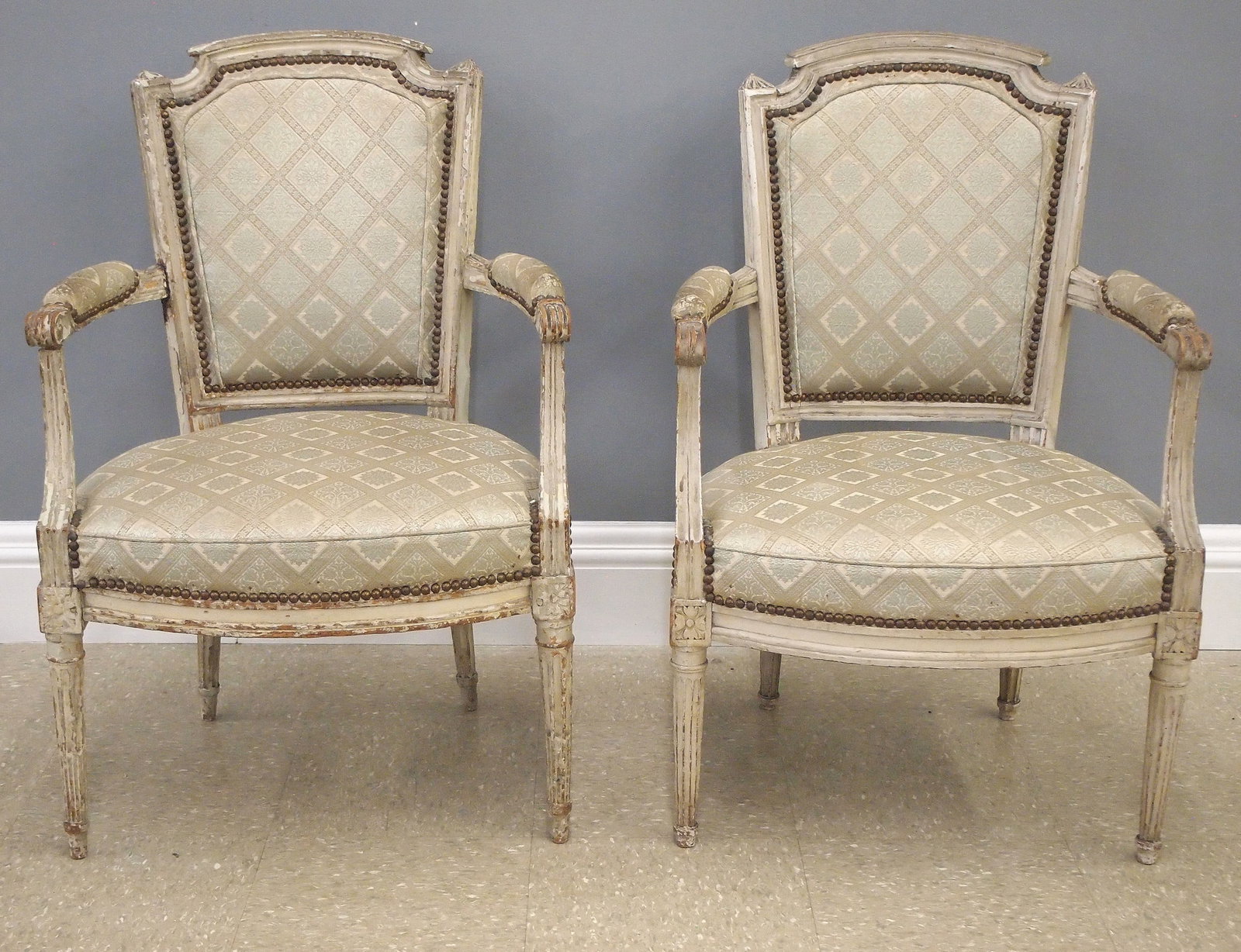 2 Louis XVI Period Fauteuils: Two 18th century French Louis XVI Period fauteuils. Mixed wood construction with carved detail and original painted finish, upholstered backs, arm rests and seats on tapered legs with fluted and stop 