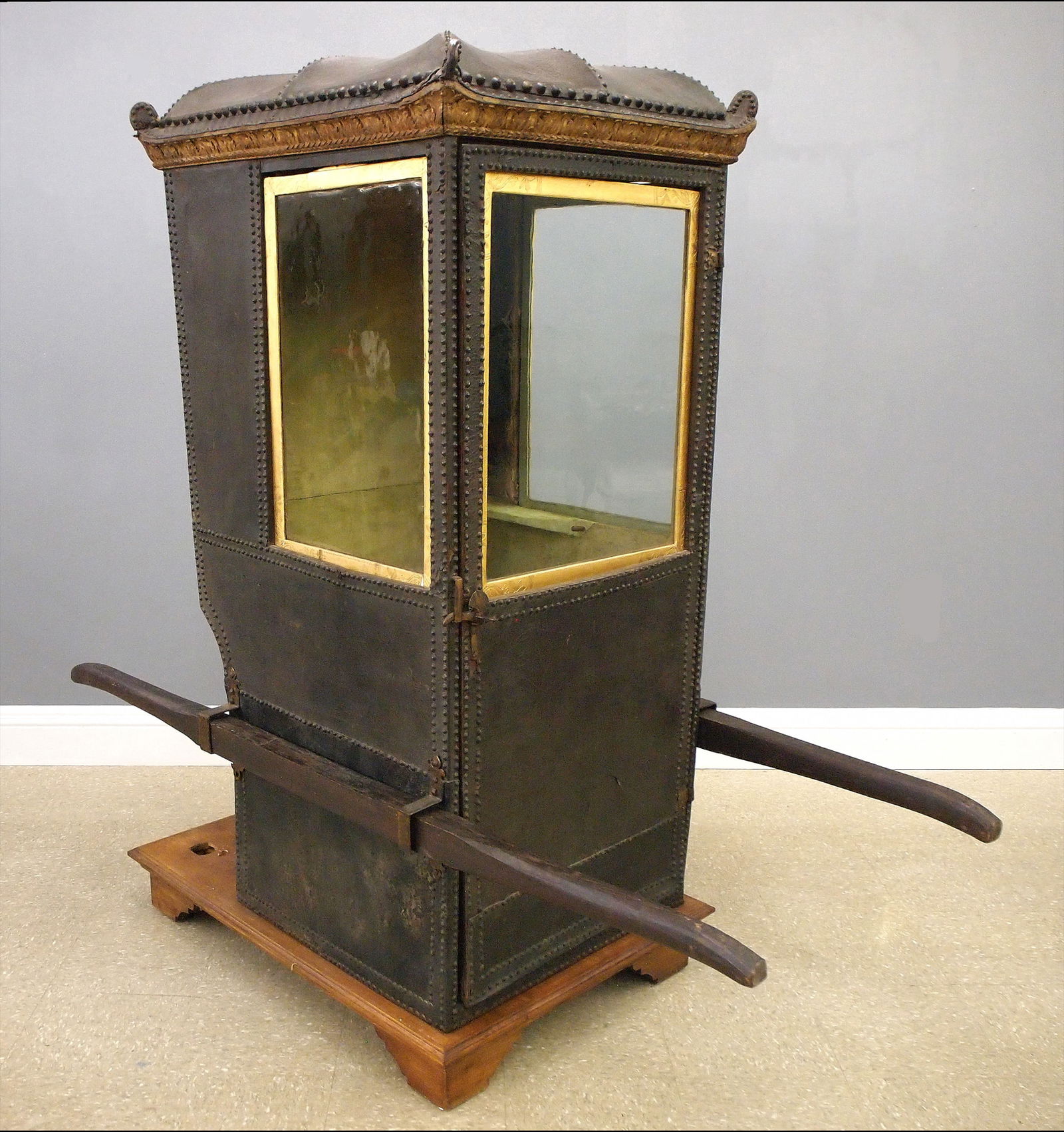 Italian Sedan Chair: An 18th century Italian Sedan chair, probably Venetian. Leather covered wooden frame with Brass tack decoration features a Pagoda form top with carved Gilded cornice over a hinged front door, sliding
