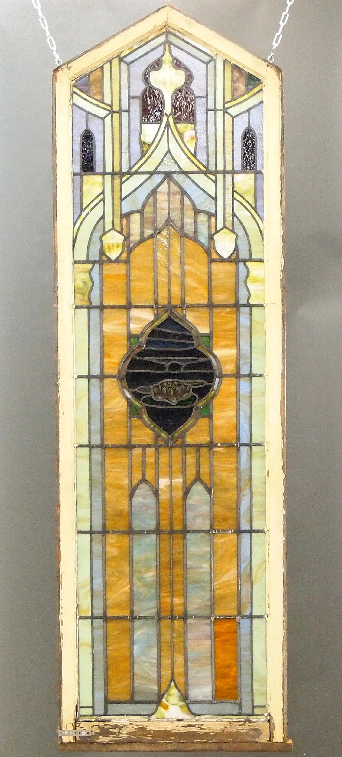 Stained Glass Window with Water Lily: A turn of the century Stained Glass window. Multi-color Leaded Glass window with reverse painted water lily decoration within a painted wooden frame with pediment top. Multiple cracked panels, frame w
