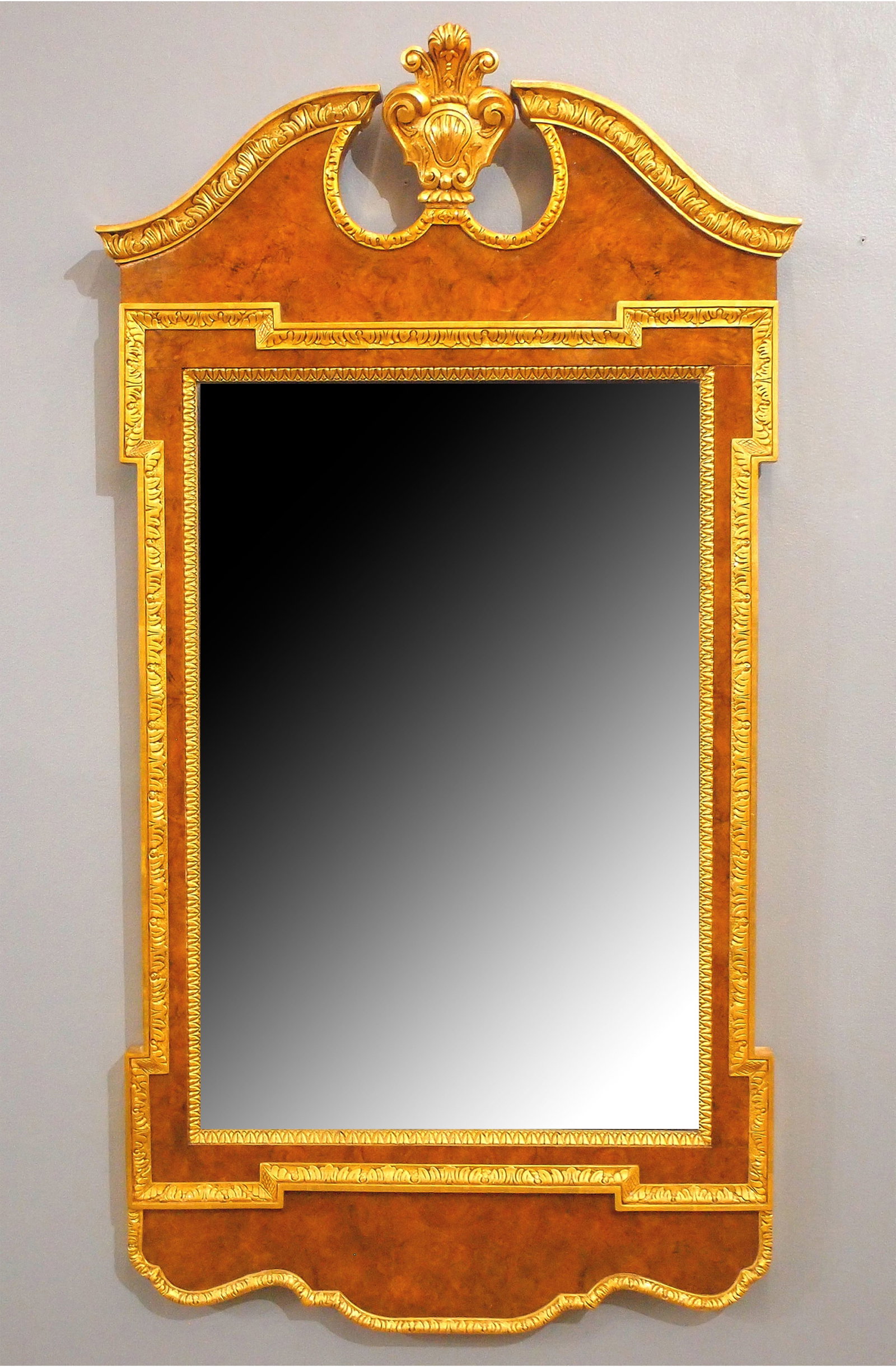 Baker Wall Mirror: A Baker George I style wall mirror. Burl Walnut frame with Gilded edge, broken arch crest with urn finial and beveled mirror. Slight wear, minor edge damage. 26 1/2 x 50" high overall. ESTIMATE $600-8