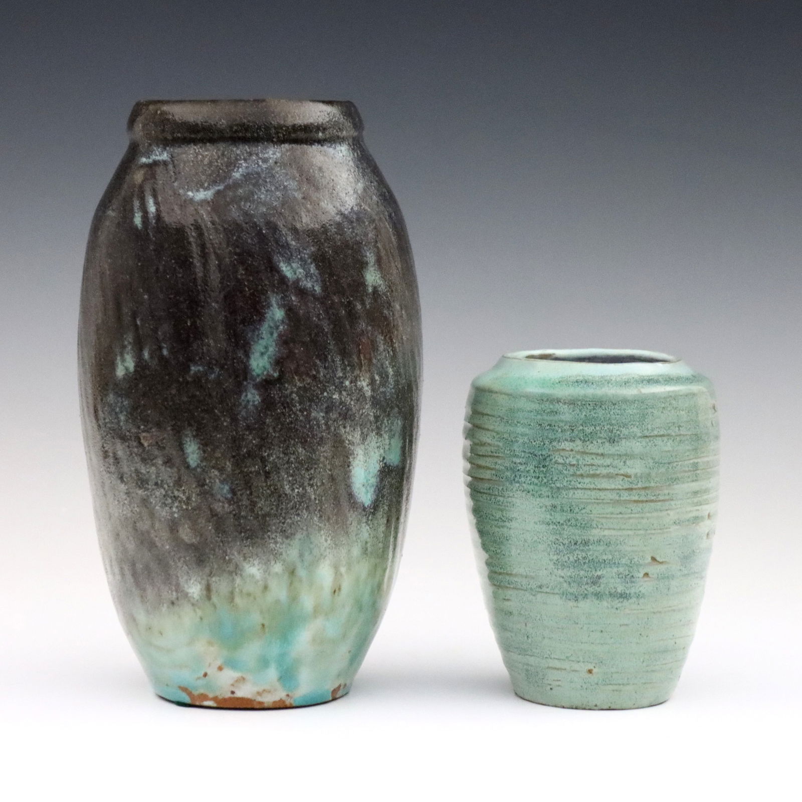 2 E. Lion Stoneware Vases: Two turn of the century Eugene Lion stoneware vases. Both tapered forms with textured bodies and glazes in various shades of Turquoise. Incised "Lion" signatures. Minor surface wear. Up to 8 1/2" high