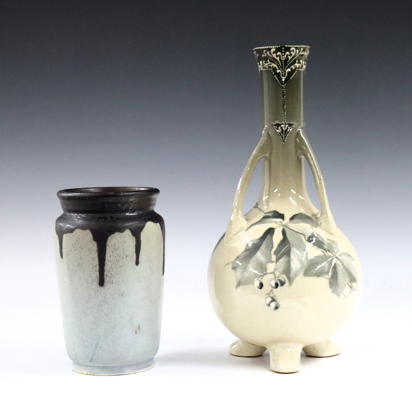 2 Roseville Art Pottery Vases: Two early 20th century Roseville Art Pottery vases. Includes a bottle form Rozane vase with three handles, tripod feet and Green foliate decoration, and an early Carnelian vase with tapered form and d