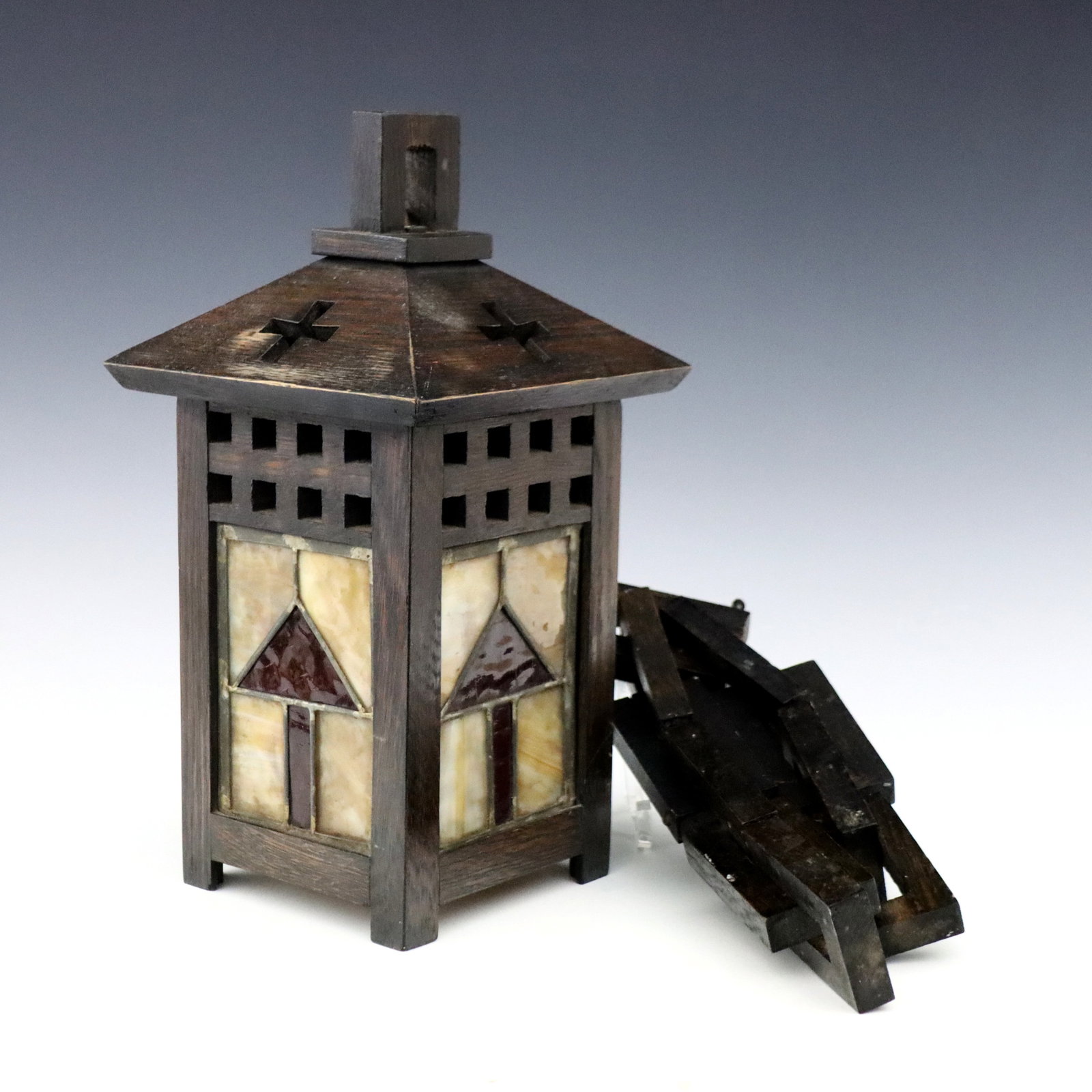 Arts & Crafts Hanging Light: An early 20th century American Arts & Crafts Period hanging light. Lantern form, pierced wooden frame with cross and lattice design over geometric Amber Slag and Ruby glass panels, hanging on a carved