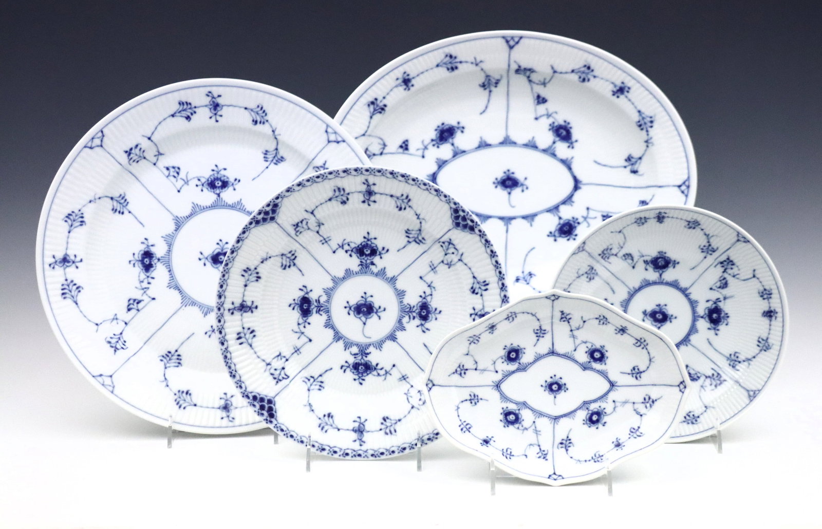 5 Royal Copenhagen Serving Dishes: Five 20th century Royal Copenhagen "Blue Fluted" pattern porcelain serving dishes. Includes an oval tray, charger, circular dish, low bowl and a scalloped tray in "Plain" and "Half Lace" patterns. Sta