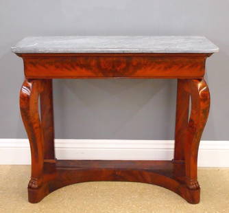 French Empire Console: An early 19th century French Empire Period console table. Figured Mahogany construction with conforming St. Anne's Marble top and a single long drawer on scrolled legs with front paw feet and shaped p