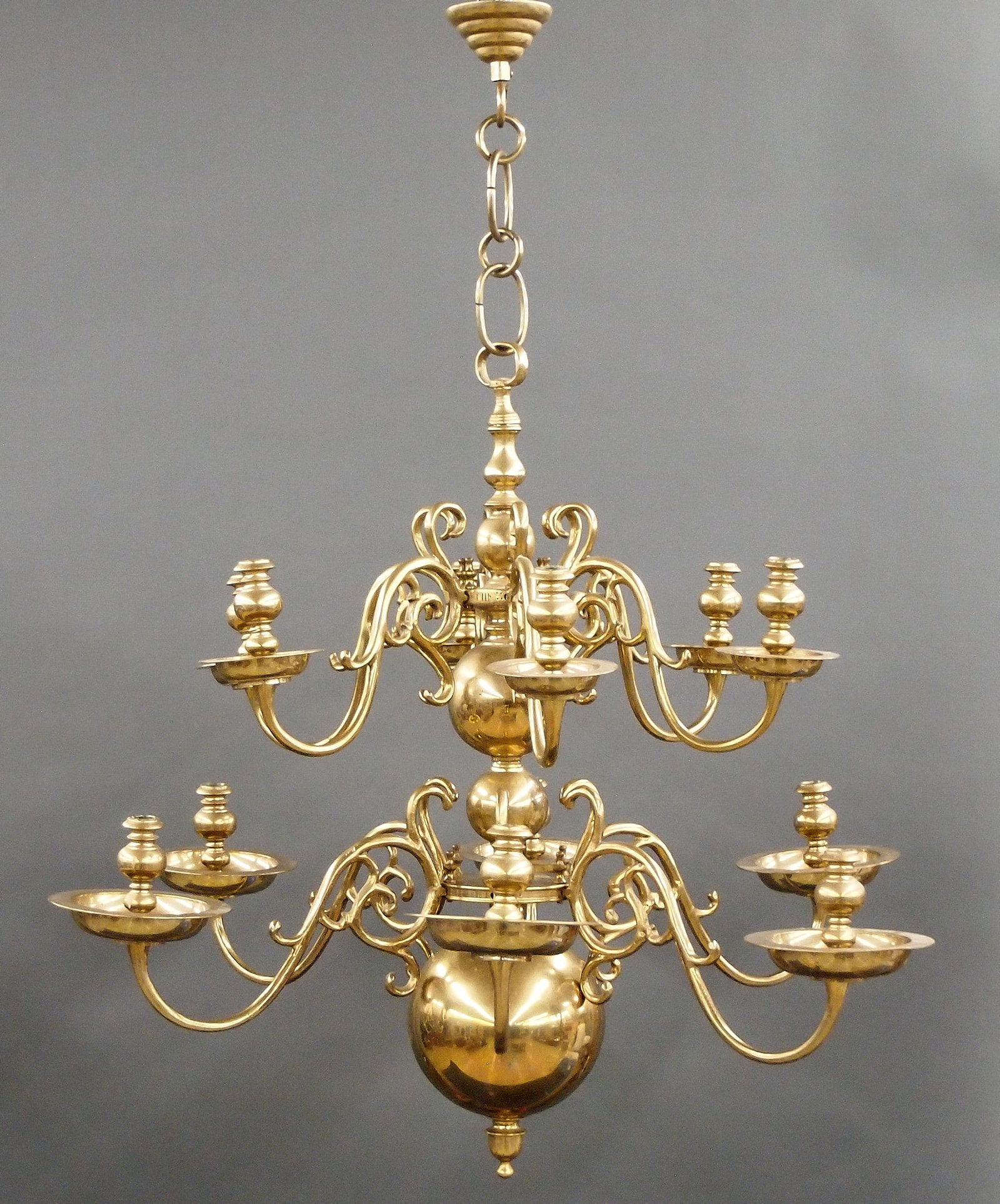 Dutch Brass Chandelier: A turn of the century Dutch Baroque style Brass candle chandelier. Twelve light design with two tiers of six removable cast Brass arms with scrolled design on a baluster form stem. Some wear and pitti
