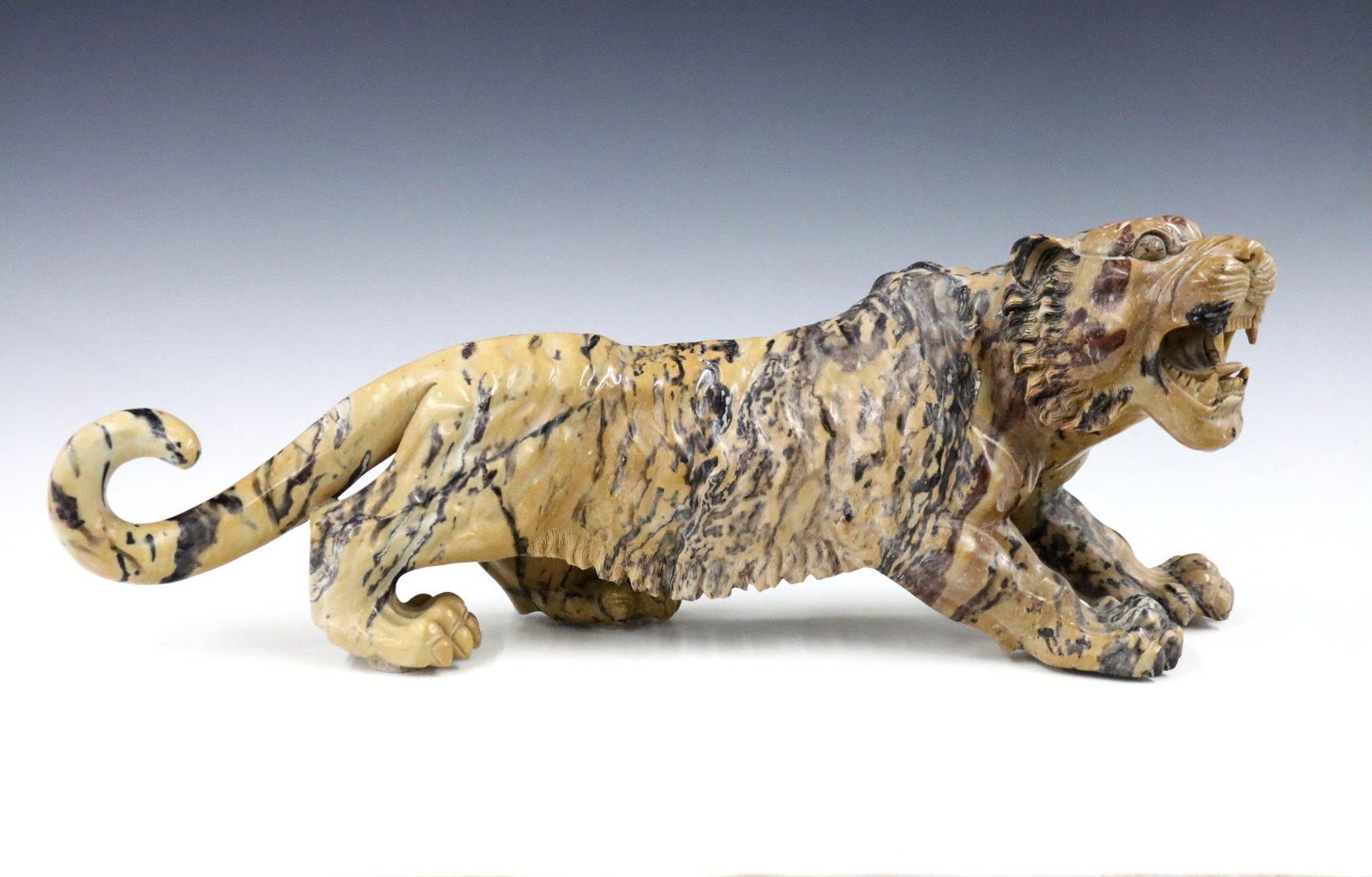 Japanese Hardstone Figure of a Tiger: A 20th century Japanese carved Brown Hardstone figure of a roaring tiger. Glued repair to tail. 19" long. ESTIMATE $200-300