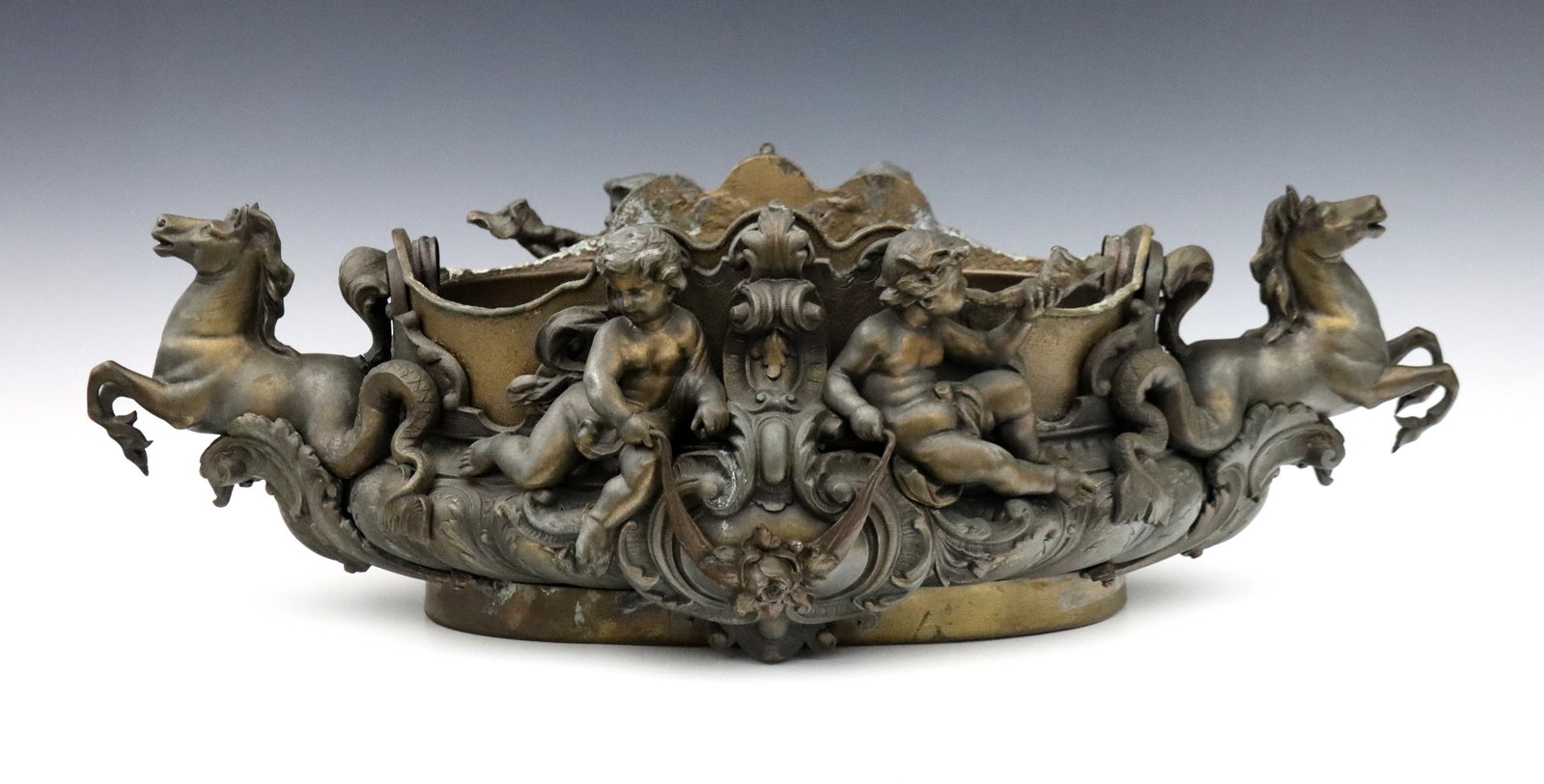French Bronze Jardiniere: An early 20th century French Bronze jardiniere. Cast Bronze with Neoclassical design depicting putti and mythological Hippocampi with lift-out Iron liner. Older refinishing with wear and some soldered