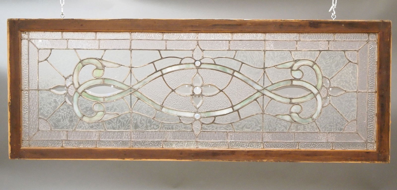 Stained & Beveled Glass Transom Window: A turn of the century Stained and Beveled Glass transom window. Beveled Fleur-de-Lis design with multi-color Leaded Glass panels with and faceted Opalescent glass accents in a stained wooden frame. Mu