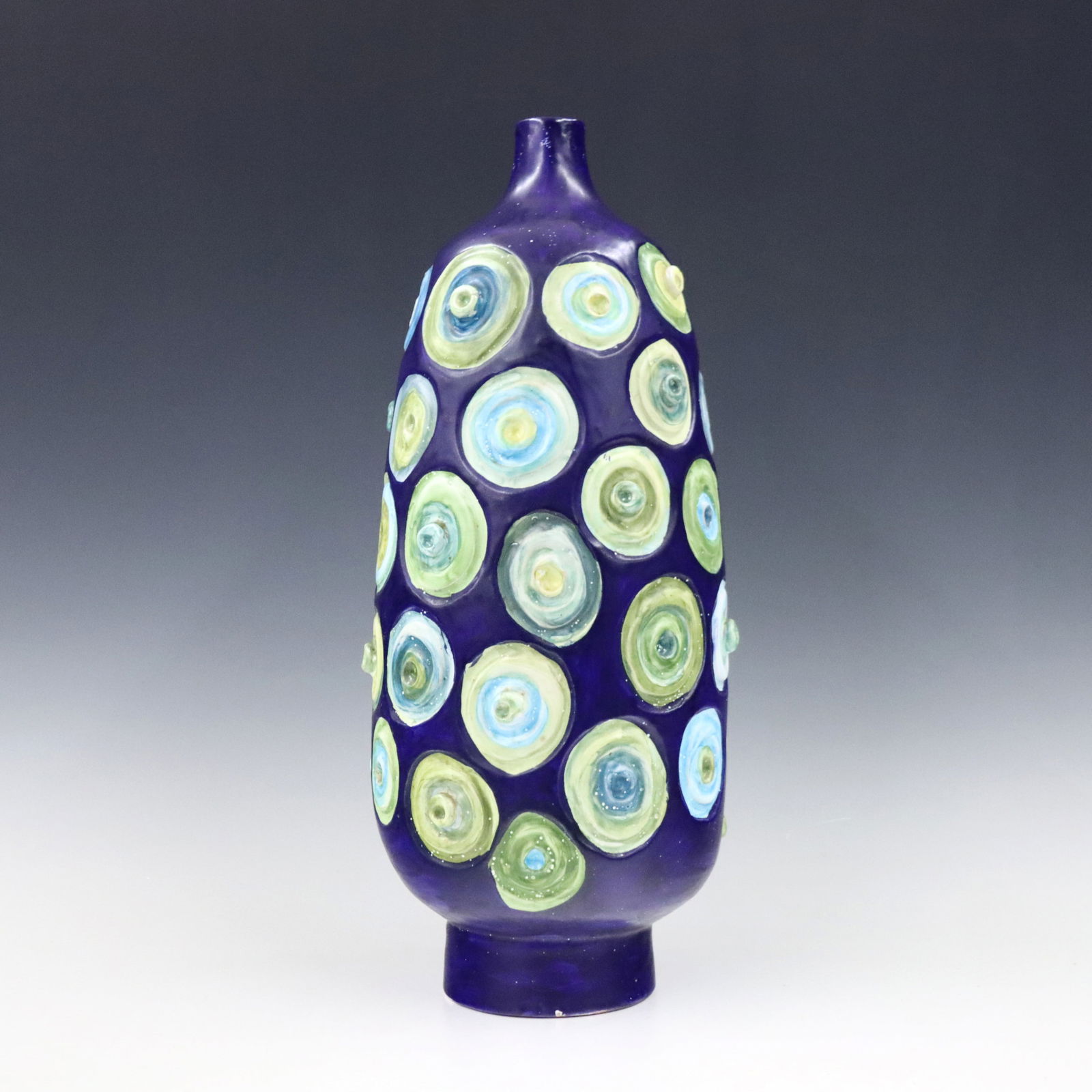 Raymor Pottery Vase: A Mid Century Modern Italian Raymor pottery vase. Tall footed form with circular relief design in shades of Blue and Green with White speckles. Signed "Italy / Raymor" with numerals "1443" and origina