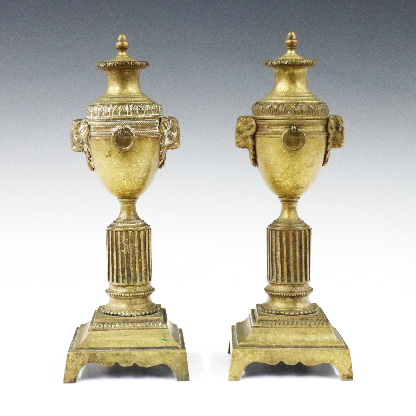 Pr French Gilded Bronze Candlesticks: A pair of 19th century French Louis XVI Style Gilded Bronze candlesticks. Two piece convertible construction with urn forms and goat masks over reeded stems and square bracket bases. Wear to finish. E