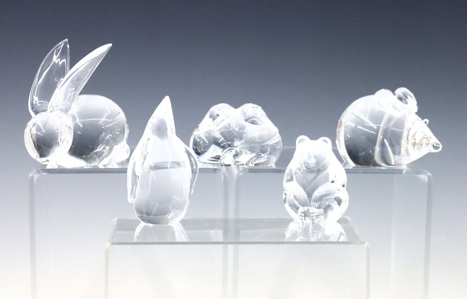 5 Steuben Crystal Animal Figures: Five mid 20th century Steuben Crystal animal figures. Includes a bunny, penguin, mouse, bear, and entwined dogs. Etched "Steuben" signatures. Minor wear. Up to 3 3/4" high. ESTIMATE $200-400