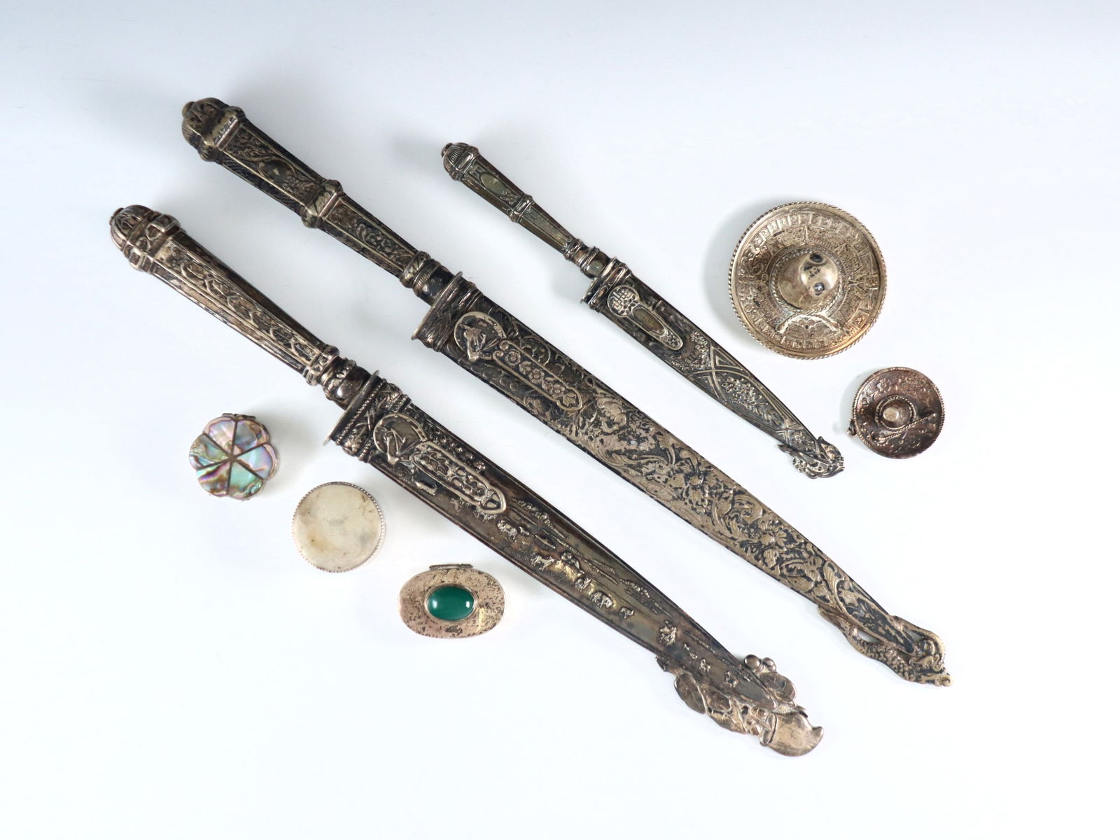 8 Silver Items: Eight 19th and 20th century Silver items. Includes three Argentinian Silverplate Gaucho knives with embossed cowboy decoration, two Mexican Sterling pill boxes with Abalone and cabochon stone accents,