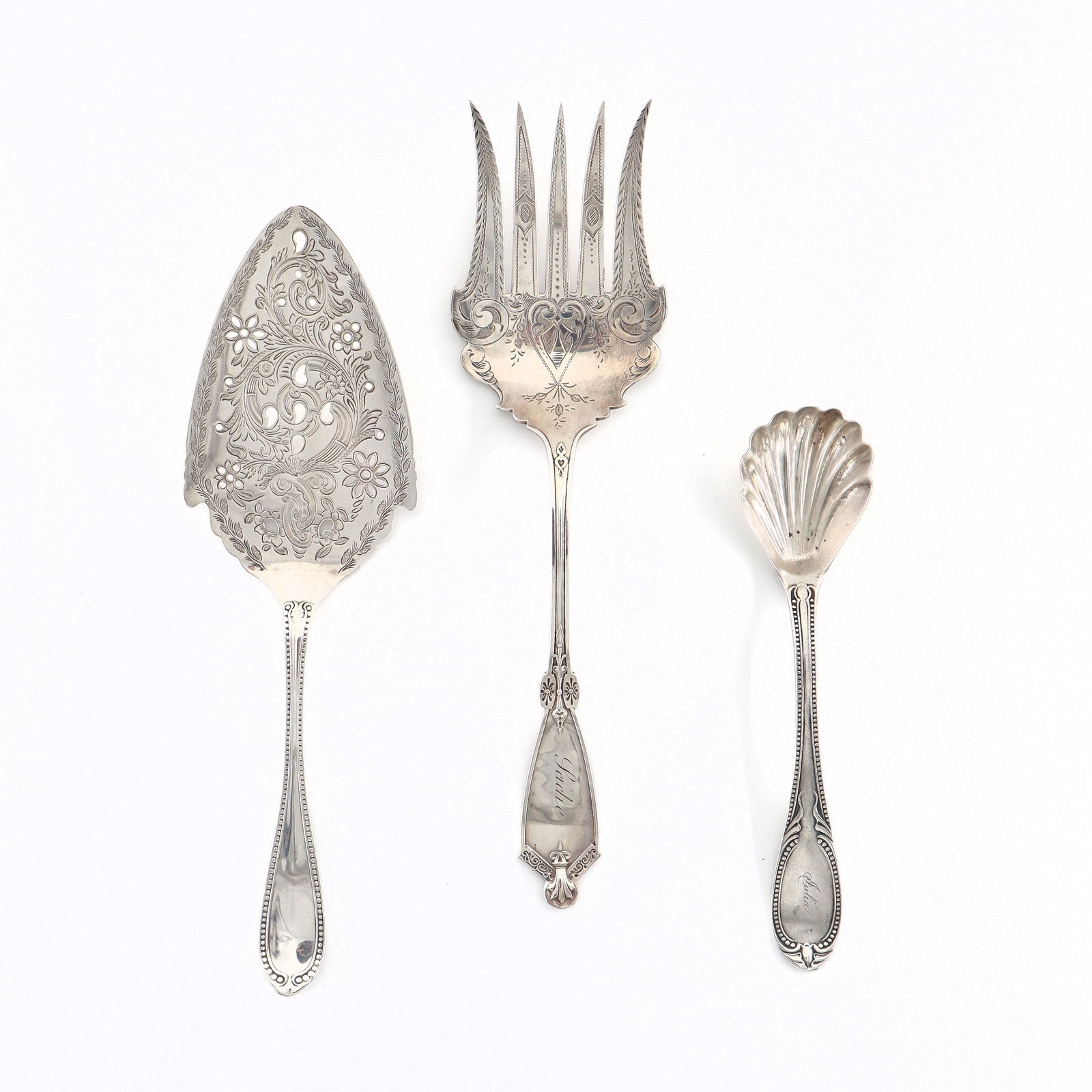 3 American Coin Silver Serving Utensils: Three 19th century American Coin Silver serving utensils with engraved decoration. Includes a meat fork by L & C, a pierced pie server and a shell form spoon by George Doty. Each with impressed marks.