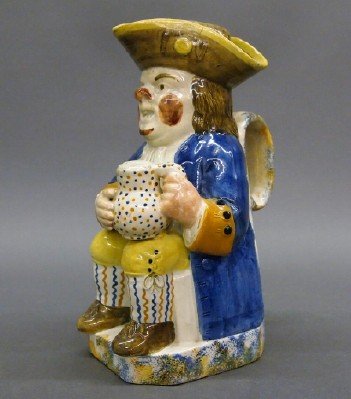 Toby jug: A late 18th/early 19th century English earthenware Toby jug. Traditional form with a seated Toby, holding an Ale jug. Decorated with polychrome glaze colors and Sponge decoration around the base. Mino