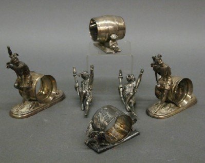 4 Silver Plated napkin rings: Four early 20th century Silver plated napkin rings. Includes two Jesters, Songbird and putti motifs. Some with wear, one Jesters with damage, includes two extra Jester figures. Up to 4" high. ESTIMATE