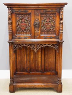 Gothic Revival Court Cupboard: A turn of the century Gothic Revival Period carved Oak court cupboard. Molded top over two doors with carved tracery, rope twist columns surmounted by carved Knights, over a open lower shelf with line