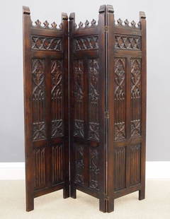 Gothic Revival Dressing Screen: A turn of the century Gothic Revival Period carved Oak dressing screen. Three panel screen with carved trefoil crown above a quatrefoil frieze and tracery panels flanking a central carved shield and l