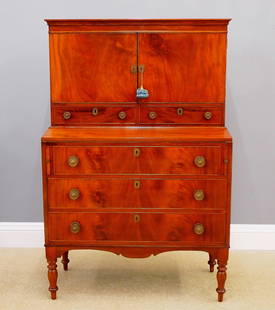 Country Sheraton Desk: A 19th century American Country Sheraton secretary desk. Mahogany construction with a two door upper section with fitted interior and two lower drawers on a base with fold out writing surface and pull