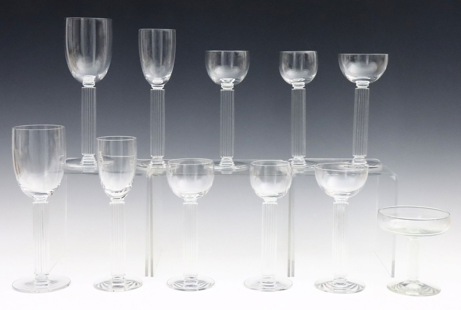 18 pc Libbey Embassy Glass Drinkware: Eighteen pieces of early 20th century Libbey "Embassy" pattern glass drinkware designed by Walter Dorwin Teague and Edwin W. Fuerst. Art Deco style with flat ribbed stem, includes 8 x 8 3/4" goblets,