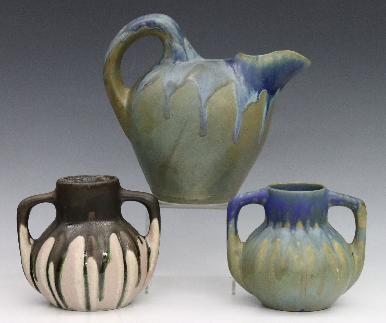 3 pc G. Metenier Art Pottery: Three pieces of early 20th century French Art Pottery by Gilbert Metenier. Blue and Brown drip glazes on Tan and Mauve grounds, includes a bulbous pitcher and two double handled gourd form vases. All