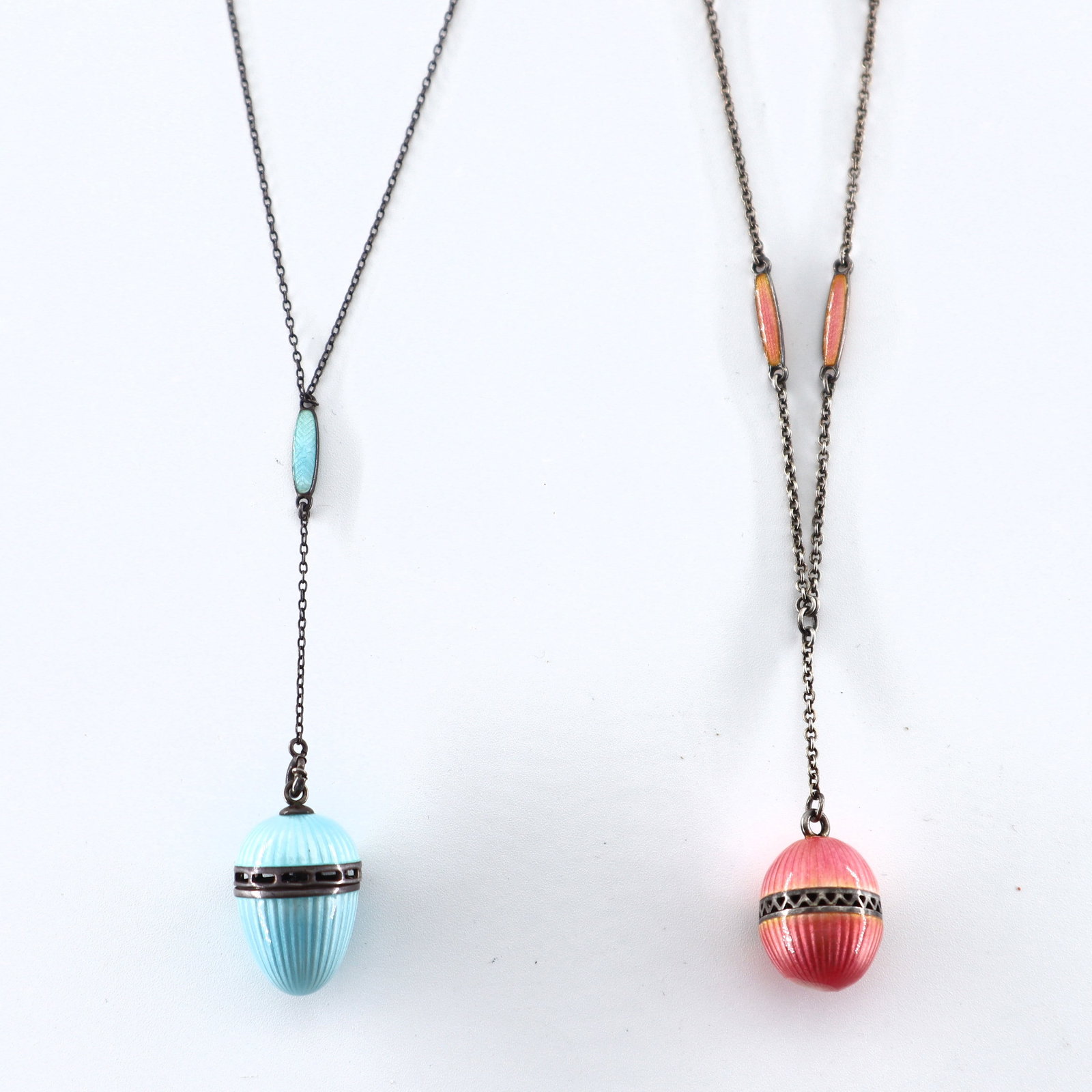 2 Guilloche Enamel Vinaigrette Necklaces: Two early 20th century guilloche vinaigrette necklaces. Pink and Blue enameled pendants that screw open and closed. Minor surface wear, Pink with some losses to enamel. Up to 13" closed. ESTIMATE $200