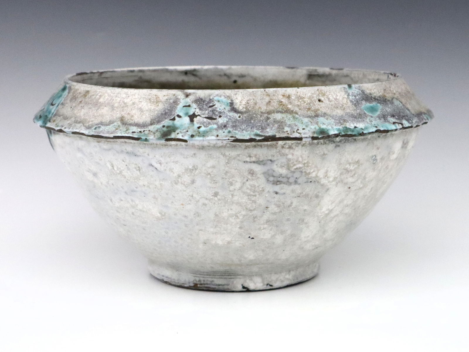 Jugtown Pottery Chinese White Bowl: A 20th century Jugtown Pottery bowl. Footed form with piecrust shoulder and mottled Chinese White glaze with Blue detail. Impressed "Jugtown Ware" mark. Minor wear, flakes and chips along shoulder edg