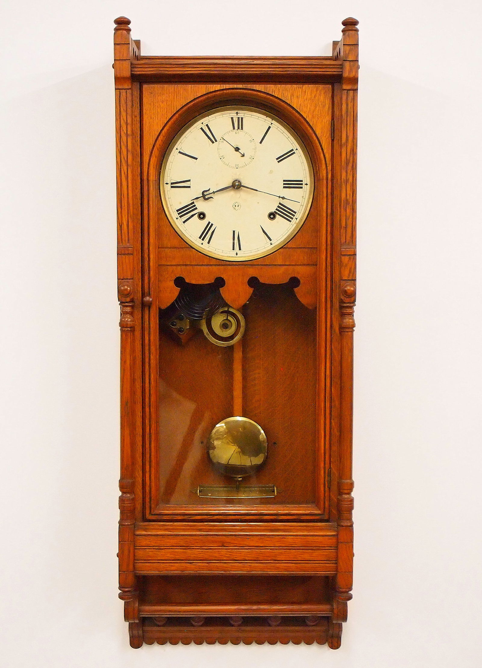 Seth Thomas Queen Anne Model Wall Clock: A turn of the century Seth Thomas Queen Anne model wall clock. 8-day spring driven time and strike movement with painted metal dial and Roman numerals. Oak case with flat molded top over an arched doo