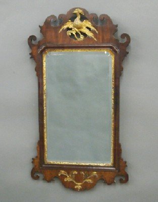 George III mirror: A late 18th/early 19th century George III wall mirror. Mahogany with Gilded detail featuring a shaped crest with carved Phoenix, carved shaped apron and ears. Older finish with some wear, restoration.