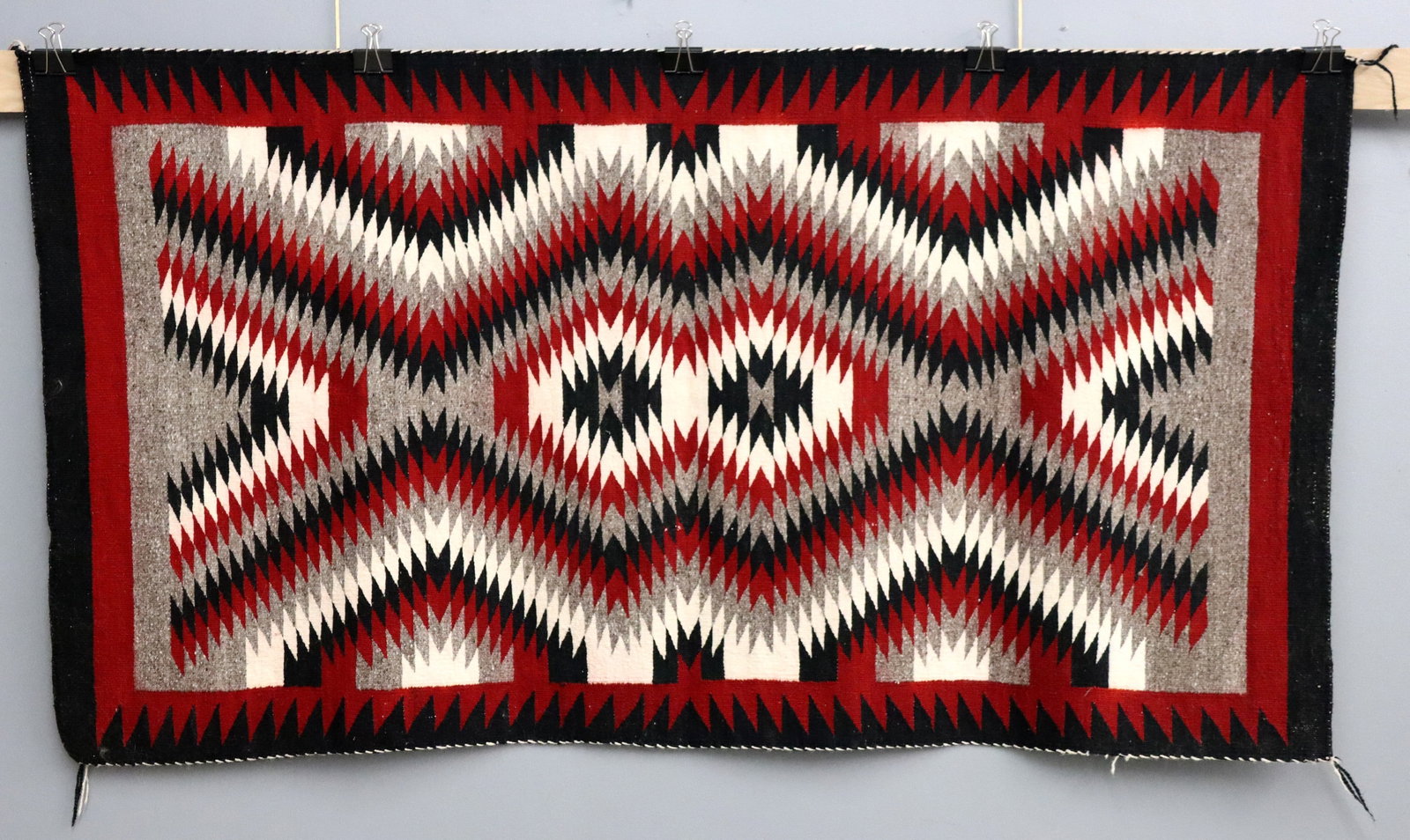 Navajo Regional Rug: A 3.1' x 5.7' mid 20th century Navajo Regional rug. Eye Dazzler geometric design in Ganado colors on a Grey field with Red and Black borders. Some wear and color bleeding. ESTIMATE $400-600