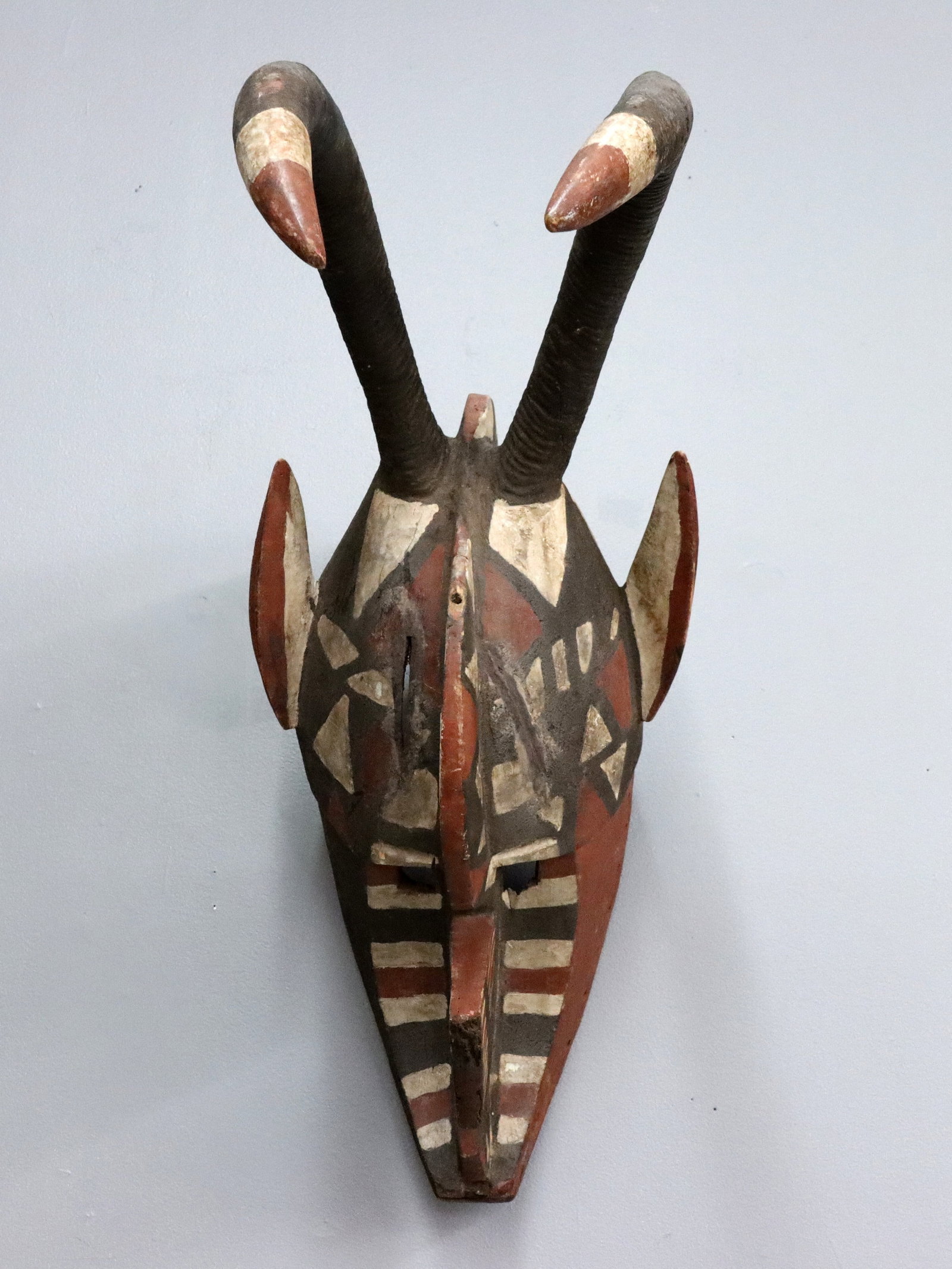 African Maasai Carved Mask: A Burkina Faso Maasai culture carved wooden mask with zoomorphic design, carved antlers and polychrome decoration. Purchased in Africa during the 1980's. Some wear and minor damage. 27" high. ESTIMATE