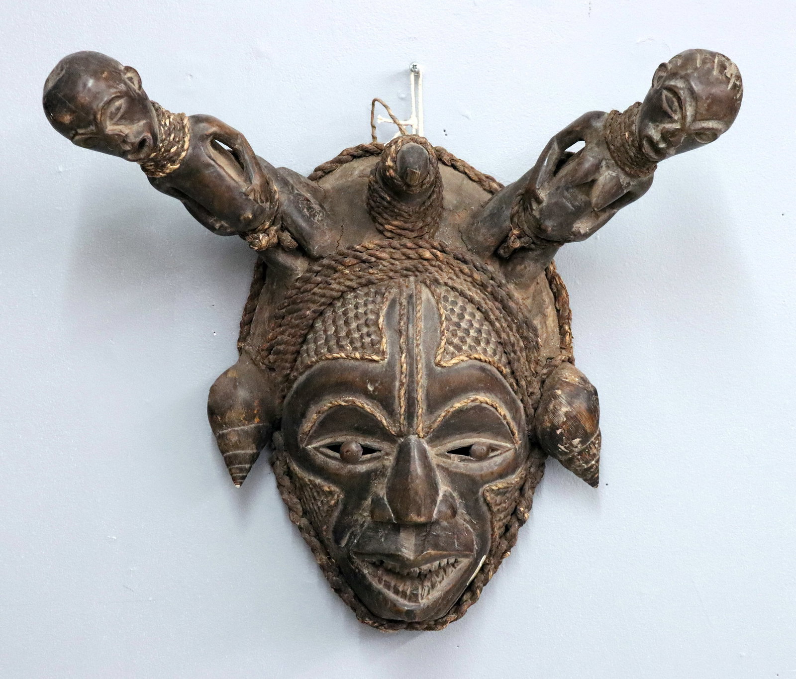 Cameroonian Carved Mask: A Cameroonian carved wooden mask with figural crests. Purchased in Africa during the 1980's. Some wear and damage. 19" high. ESTIMATE $100-200