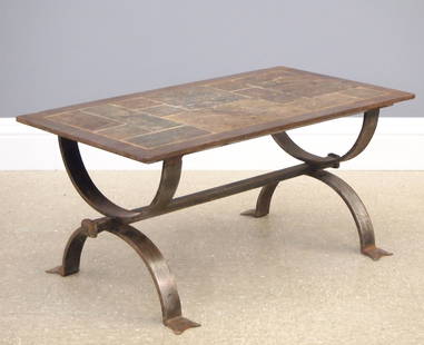 French Iron Coffee Table: A Mid Century Modern French coffee table in the manner of Jacques Adnet. Scrolled wrought iron base with an inlaid slate top. Some wear and minor damage to slate. 36 3/4 x 20 1/4 x 17" high overall. E