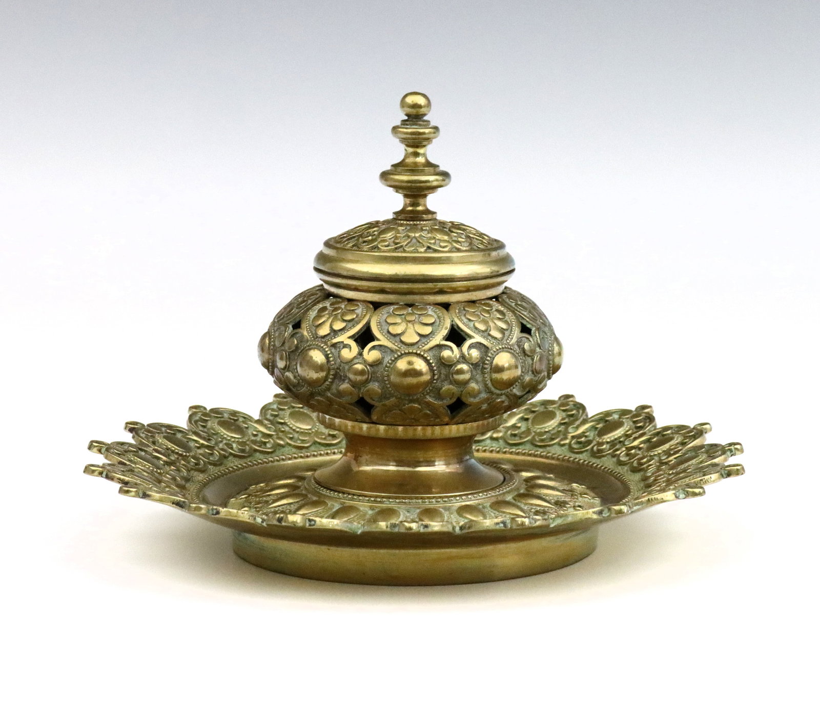 Bronze Inkwell: An early 20th century Bronze inkwell. Pierced floral design on a circular scalloped tray. Some oxidation, minor wear and pitting. 8" diameter x 5 1/4" high overall. ESTIMATE $100-150