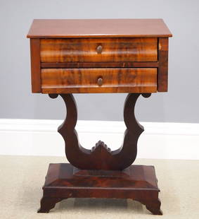American Empire Side Table: A 19th century American Empire Period side table. Figured Mahogany construction featuring a rectangular top over two drawers with curved fronts on a lyre form standard with step-molded base with shape