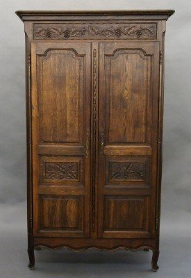 French Oak armoire: A turn of the century French Oak armoire. Molded lift off cornice above a frieze with carved vintage design and two three panel doors with the original Iron hinges above a shaped apron and simple cabr