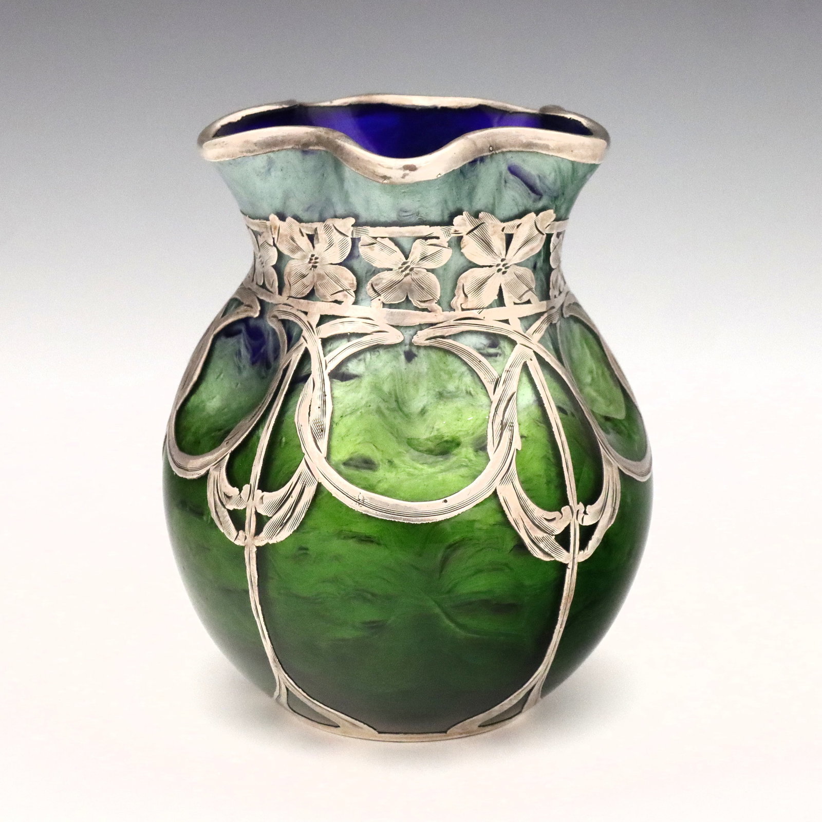 Loetz Titania Sterling Overlay Vase: A turn of the century Loetz Titania Art Glass vase with Sterling Silver overlay. Pinched glass body with ruffled rim in mottled shades of Iridescent Blue and Green with a La Pierre Art Nouveau Sterlin