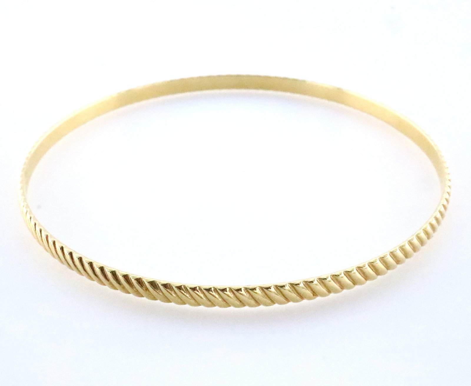 14k Gold Bangle: A 14k Gold bangle bracelet with gadrooned design. Marked faintly "14k" in cartouche. 8.1 grams total. Minor surface wear. 7 3/4" interior circumference. ESTIMATE $400-600