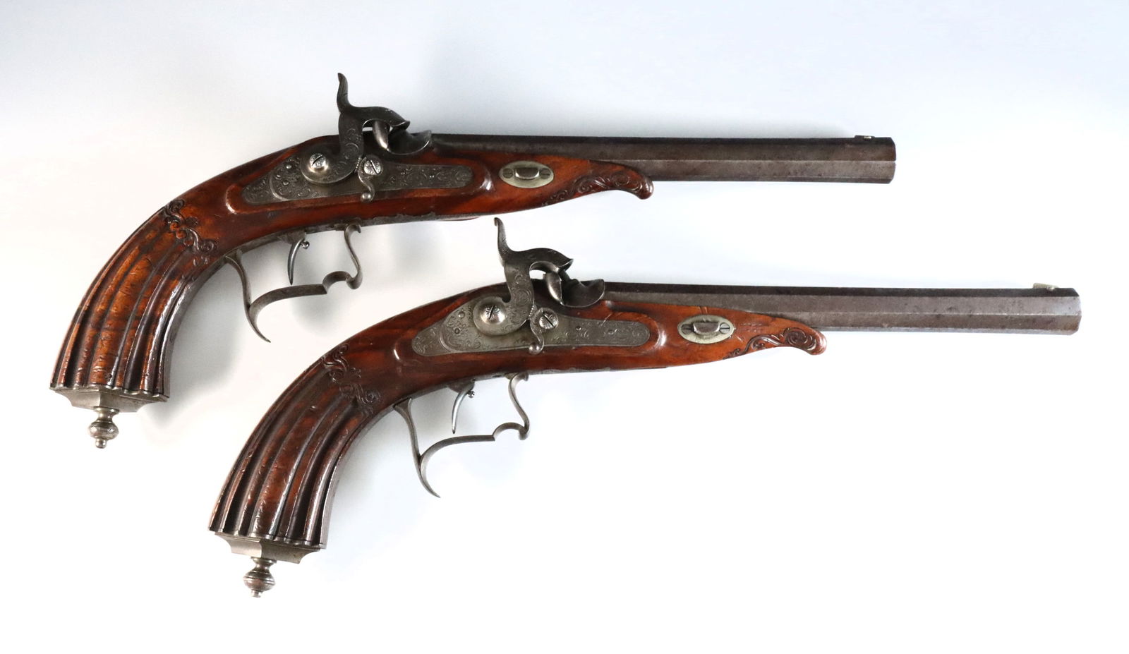Pr French Percussion Pistols: A pair of 19th century French percussion pistols. .52 caliber, muzzleloading pistol with 8 1/2" octagonal barrels, carved Walnut fluted grips, engraved dolphin form hammers, side plates, trigger guard