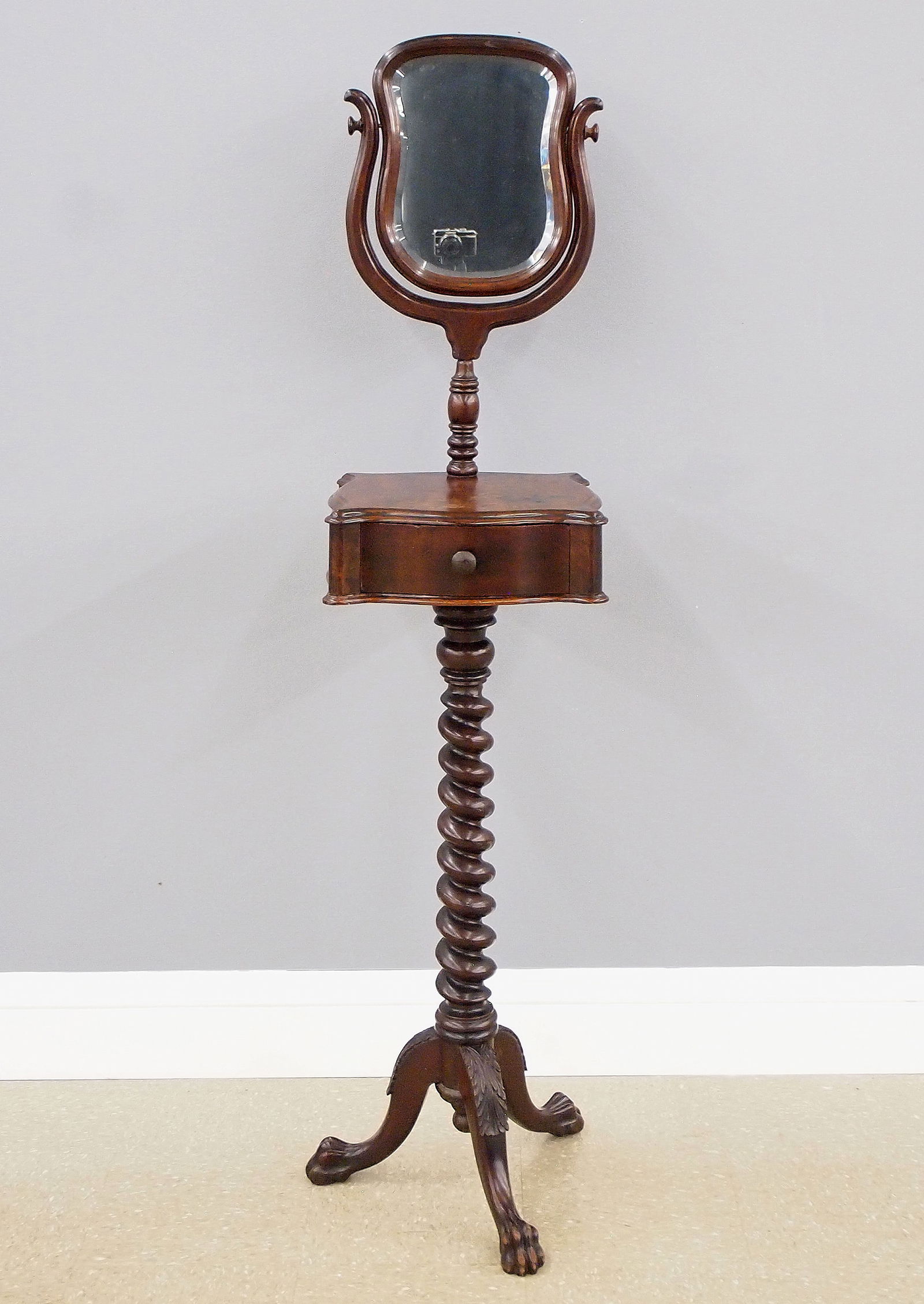 Victorian Shaving Stand: A late 19th century Victorian Period shaving stand. Walnut construction with a shaped swivel mirror on an upper shelf with dovetailed drawer, turned rope twist stem and tripod base with cabriole lags.
