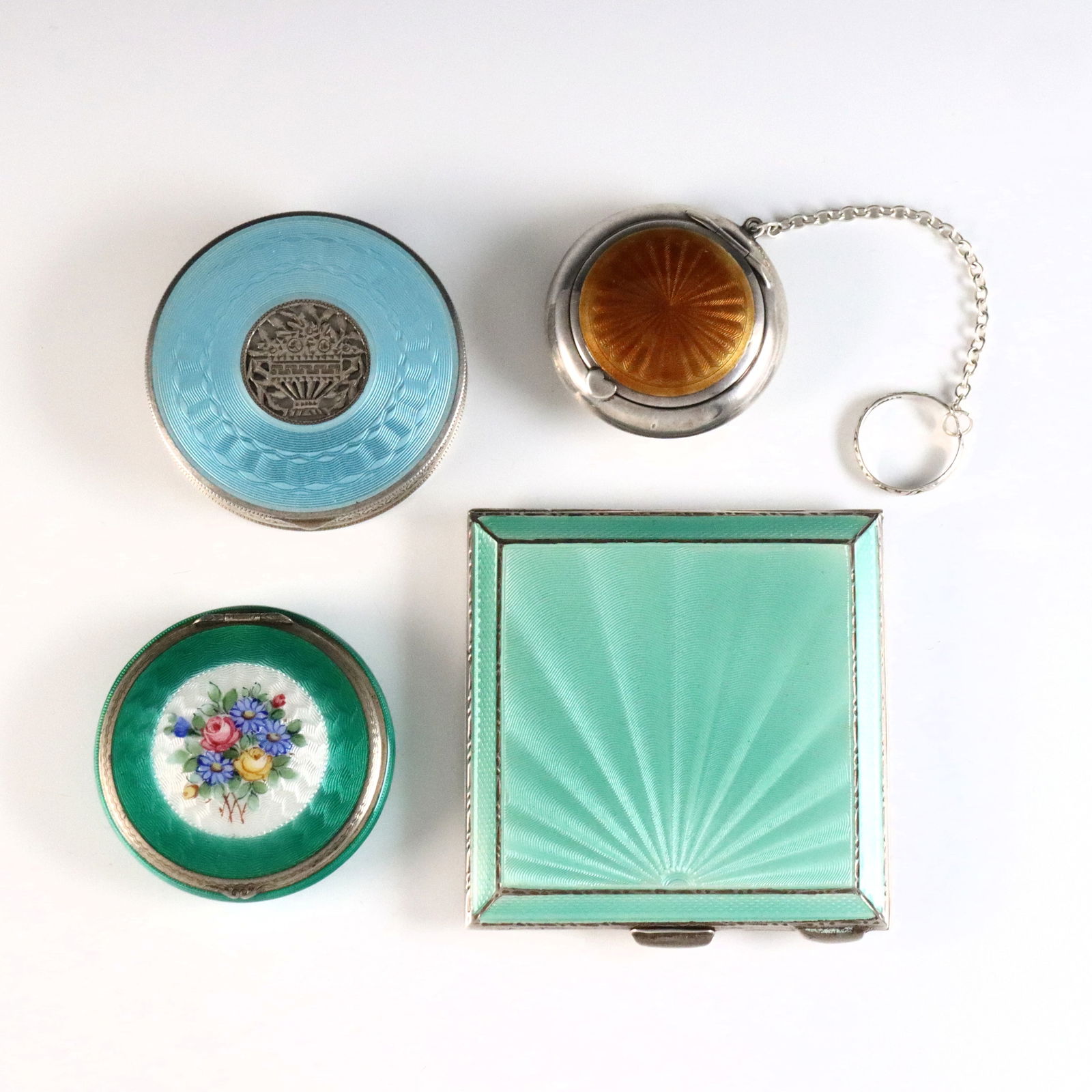 4 Silver Guilloche Cases: Four early 20th century Sterling Silver cases with Guilloche enamel decoration. Includes a square Green English compact by Henry Clifford Davis, a Light Blue Austrian compact, a floral Green American