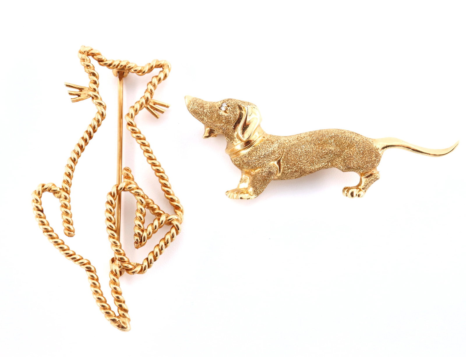 2 14k Gold Animal Brooches: Two 14k Gold animal form brooches. Includes a textured Dachshund with Diamond chip eye and a cat with twisted design. Both marked "14k". 9.5 grams total. Slight wear. Up to 2" high. ESTIMATE $600-800