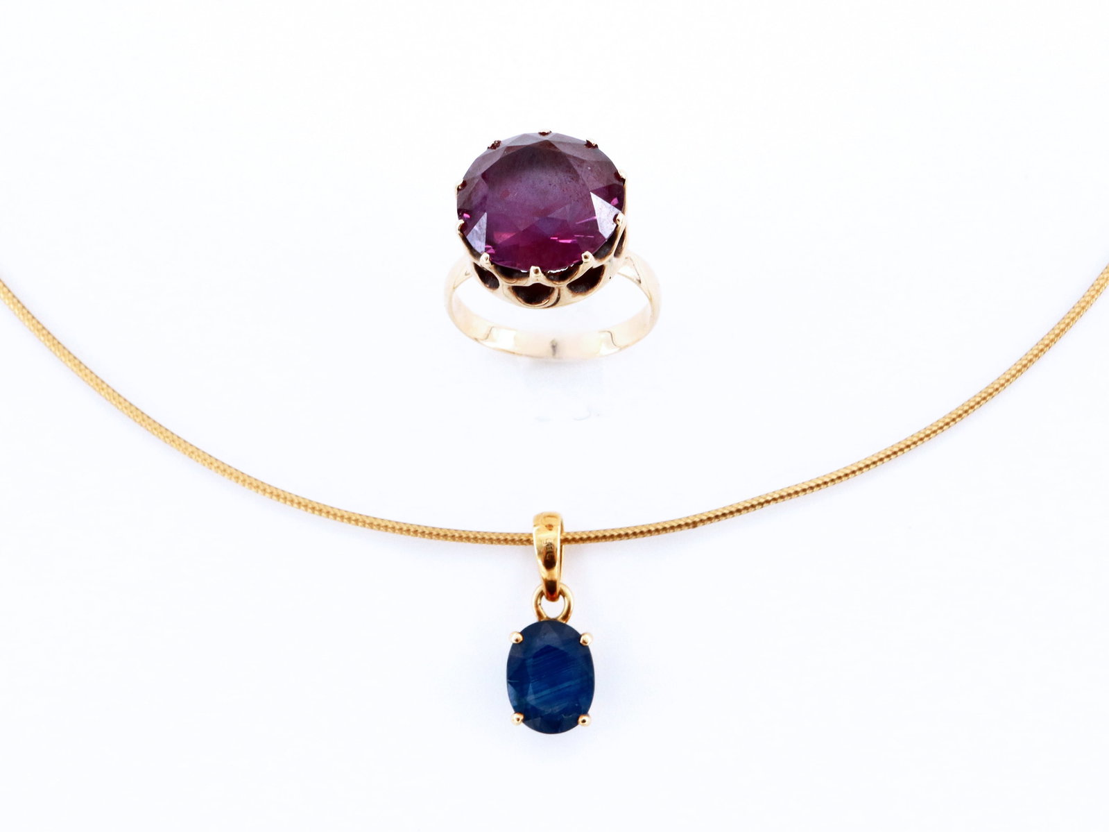 2 pc 14k Gold & Sapphire Jewelry: Two pieces of 14k Gold and Sapphire jewelry. Includes an Italian pendant necklace with oval cut prong set Sapphire approx. 7 x 9 mm on a wired Omega chain, and a ring with round cut Purple Sapphire ap