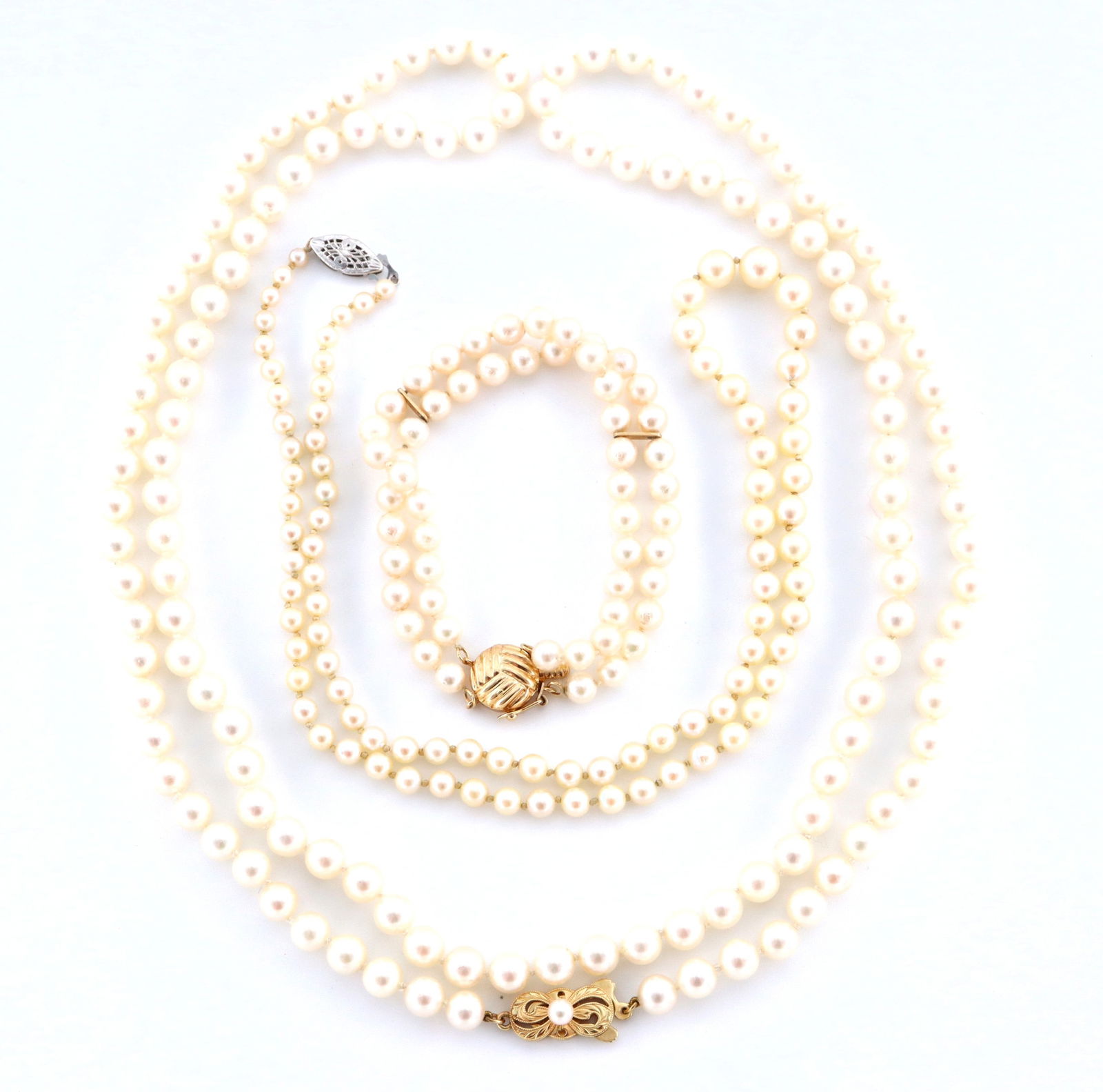 3 pc 14k Gold Pearl Jewelry: Three pieces of Pearl jewelry with 14k Gold clasps. Includes two single strand necklaces and a double strand bracelet with bar spacers. Each clasp marked "14k". 74.19 grams total. Minor surface wear.
