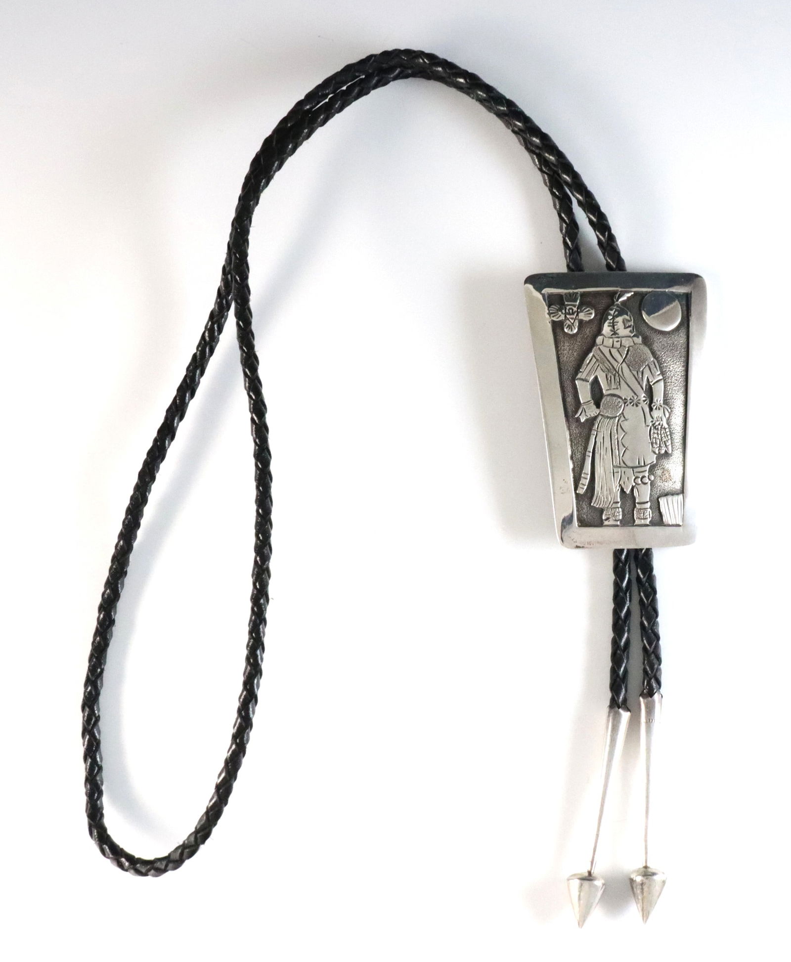 L. Nez Hopi Style Sterling Bolo Tie: A vintage Hopi style Sterling Silver Bolo tie attributed to Navajo artist Leonard Nez. Features a trapezoidal clasp with Kachina design on a braided leather tie. Incised "Nez" with a pictorial mark (n