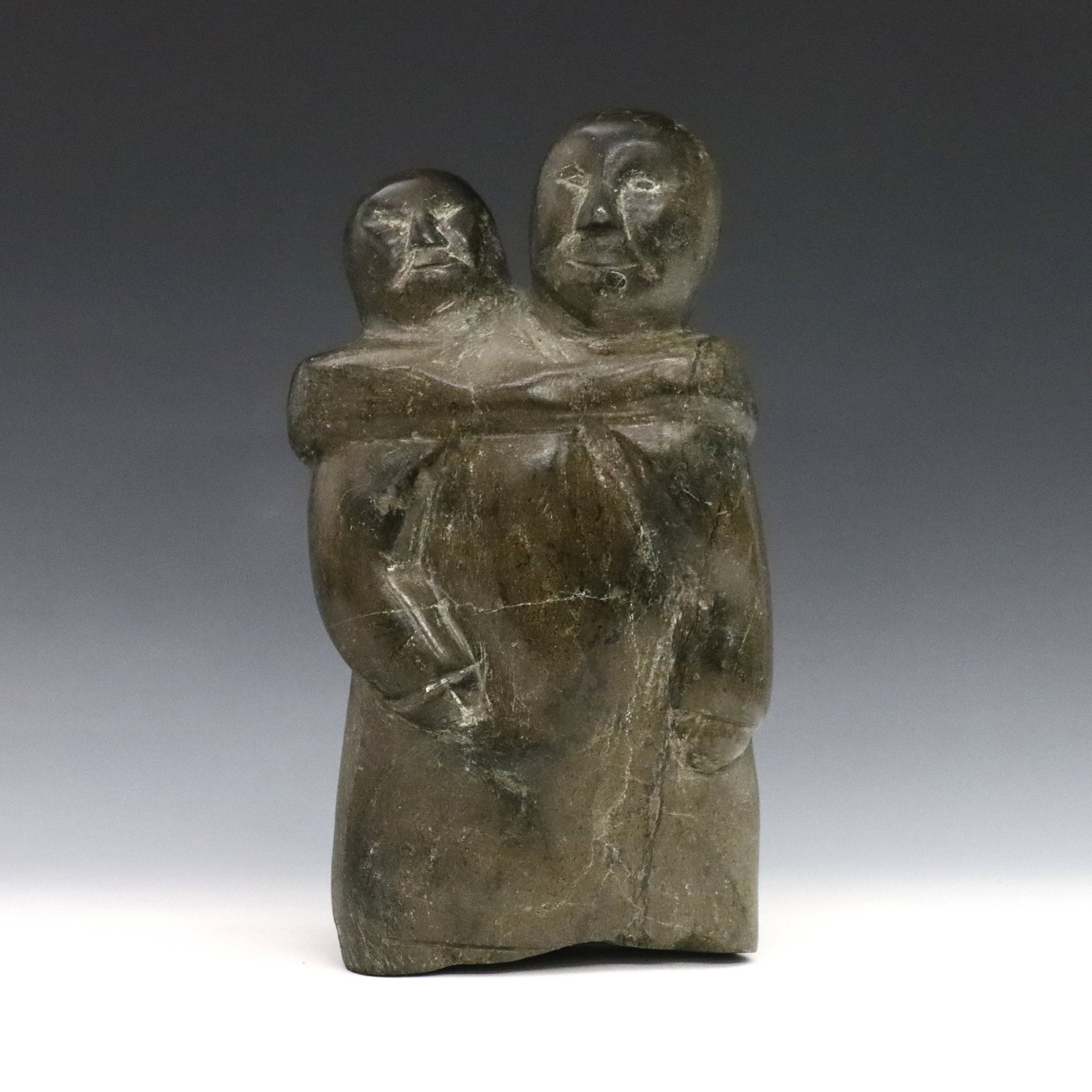A. Aningmiuq Inuit Stone Mother & Child: Attributed to Alashua Aningmiuq, Inuit (Nunavut, Cape Dorset), 1914-1972. A mid 20th century carved Serpentine figure of a mother with a child at her back. Unsigned, retains paper labels at back with 